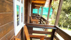 A wooden deck with benches and tables, surrounded by a wooden railing. - B R Cottages (Canacona)