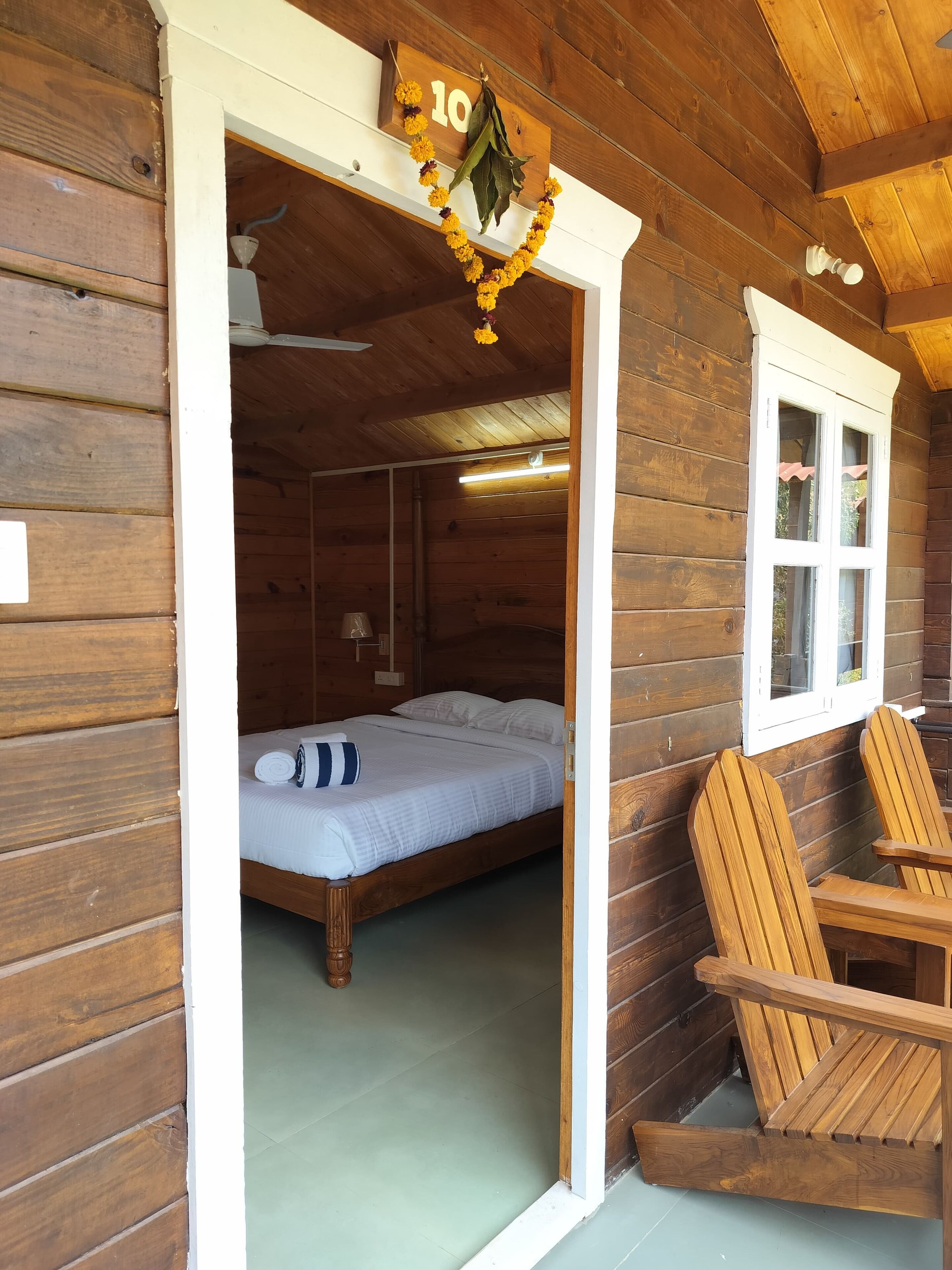 A wooden cabin room with a bed, a rocking chair, and a window.