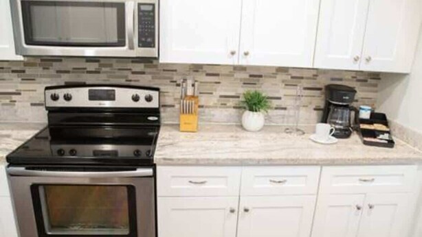 A kitchen with a microwave, stove, and cabinets. - Ocean Breeze Bungalow 4BR 2BA W/Pool (Hollywood)