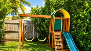 A wooden playground with a slide and swings. - Ocean Breeze Bungalow 4BR 2BA W/Pool (Hollywood)