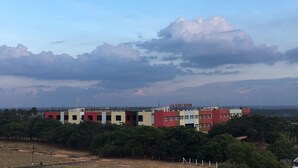 Un edificio de varios pisos con techo plano, rodeado de vegetación.