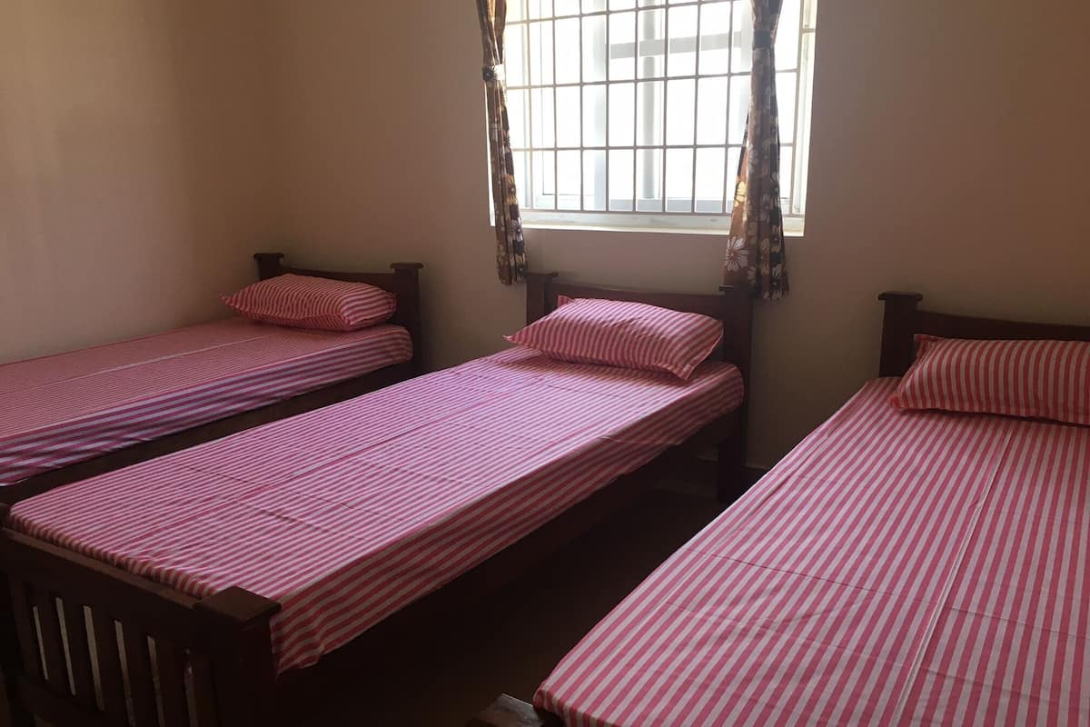 A room with three single beds, each with a striped pink and white bedspread.