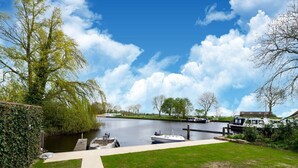 Un canal où sont amarrés des bateaux, une zone herbeuse et un ciel dégagé.