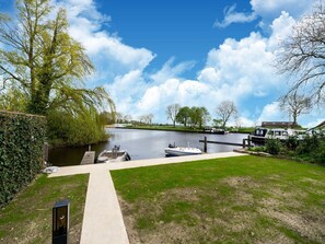 Un canal où sont amarrés des bateaux, une zone herbeuse et un ciel dégagé.