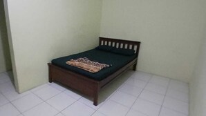 Una habitación pequeña con una cama individual, cabecera de madera y edredón estampado.
