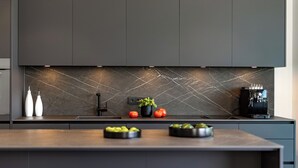 Eine moderne Küche mit dunklen Schränken, einer Marmor-Spritzschutzwand und einer Kaffeemaschine.