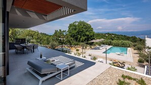 Ein moderner Außenbereich mit Pool, Sitzgelegenheiten und einem schönen Ausblick.