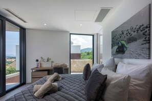 A modern bedroom with a large bed, a view of the city, and a painting of a turtle.