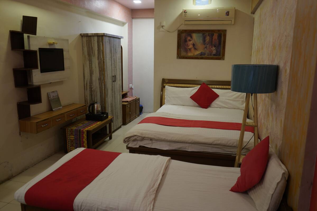 Habitación de hotel con dos camas, un televisor, un cuadro y un armario.