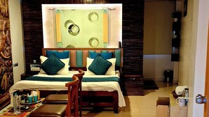 Ein Hotelzimmer mit Bett, Schreibtisch, Stuhl, einem kleinen Tisch und einem dekorativen Teppich.