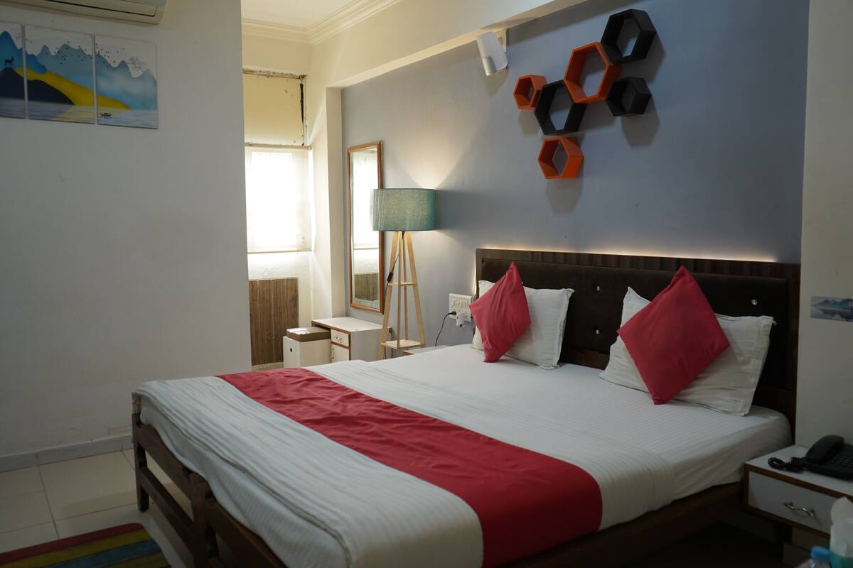 Habitación de hotel impecable con una cama grande, una mesita de noche, una lámpara y un calentador de pared.