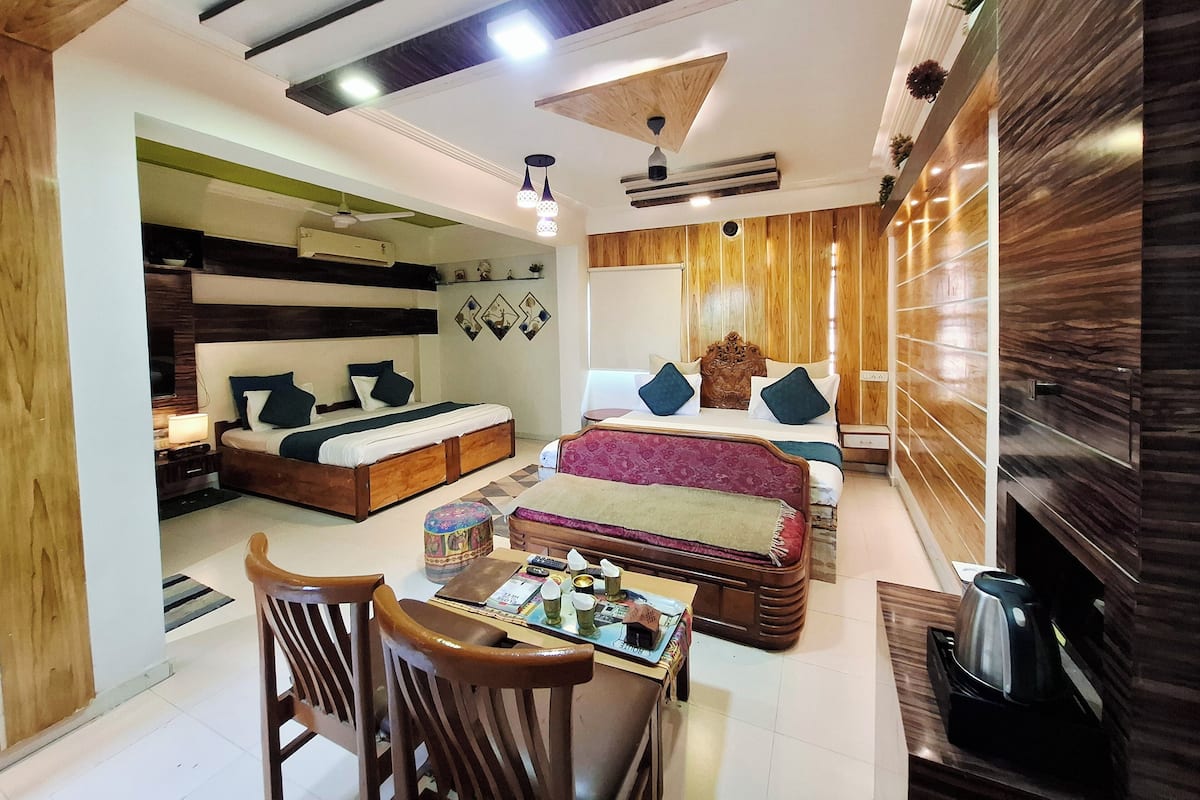 Una habitación de hotel moderna con una cama grande, un sofá, una mesa de comedor con sillas y una cafetera.