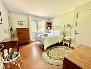 A bedroom with a bed, a dresser, a chair, a nightstand, a lamp, and a window. - Porchside Retreat: Sauna and Treeline Backyard (Meaford)