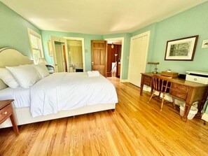 A bedroom with a large bed, wooden floor, a desk, and a chair. - Porchside Retreat: Sauna and Treeline Backyard (Meaford)