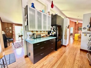 A kitchen with a central island, wooden flooring, and cabinets with a light-colored countertop. - Porchside Retreat: Sauna and Treeline Backyard (Meaford)