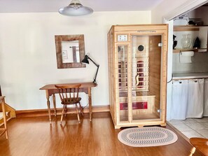 A room with a wooden desk, chair, and a cabinet with glass doors. - Porchside Retreat: Sauna and Treeline Backyard (Meaford)