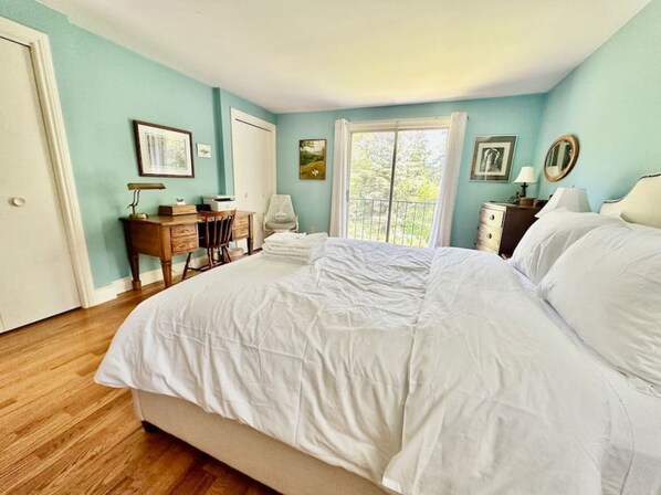 Une chambre avec un grand lit, un bureau et une chaise. Il y a une fenêtre avec des rideaux.