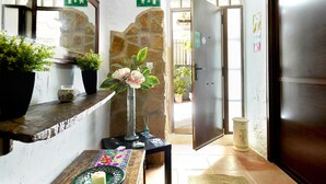 A reception area with a stone wall, a wooden door, a reception desk, and a potted plant. - Apartment 'Guadalentin' with Private Terrace, Wi-Fi and Air Conditioning (Quesada)
