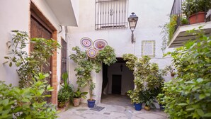 A courtyard with potted plants, a wooden door, and a wall-mounted lamp. - Apartment 'Guadalentin' with Private Terrace, Wi-Fi and Air Conditioning (Quesada)