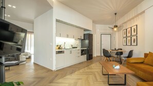 A modern kitchen with white cabinets, a built-in oven, and a dining area with a table and chairs.
