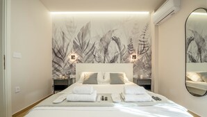 A modern hotel room with a large bed, two bedside tables, a wall-mounted mirror, and a floral wallpaper design.
