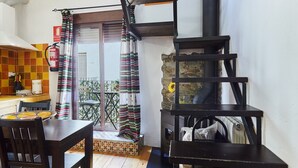 A kitchen with a stove, a dining table with chairs, a staircase, and a view of the outside. - Apartment 'Cazorla Rural Guadiana' with Balcony, Wi-Fi and Air Conditioning (QUESADA)