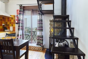 A kitchen with a dining table and chairs, a fire extinguisher, a staircase, and a view of the outside. - Apartment 'Cazorla Rural Guadiana' with Balcony, Wi-Fi and Air Conditioning (QUESADA)