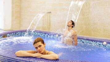 A hot tub with two people, one sitting and one standing, with water jets.