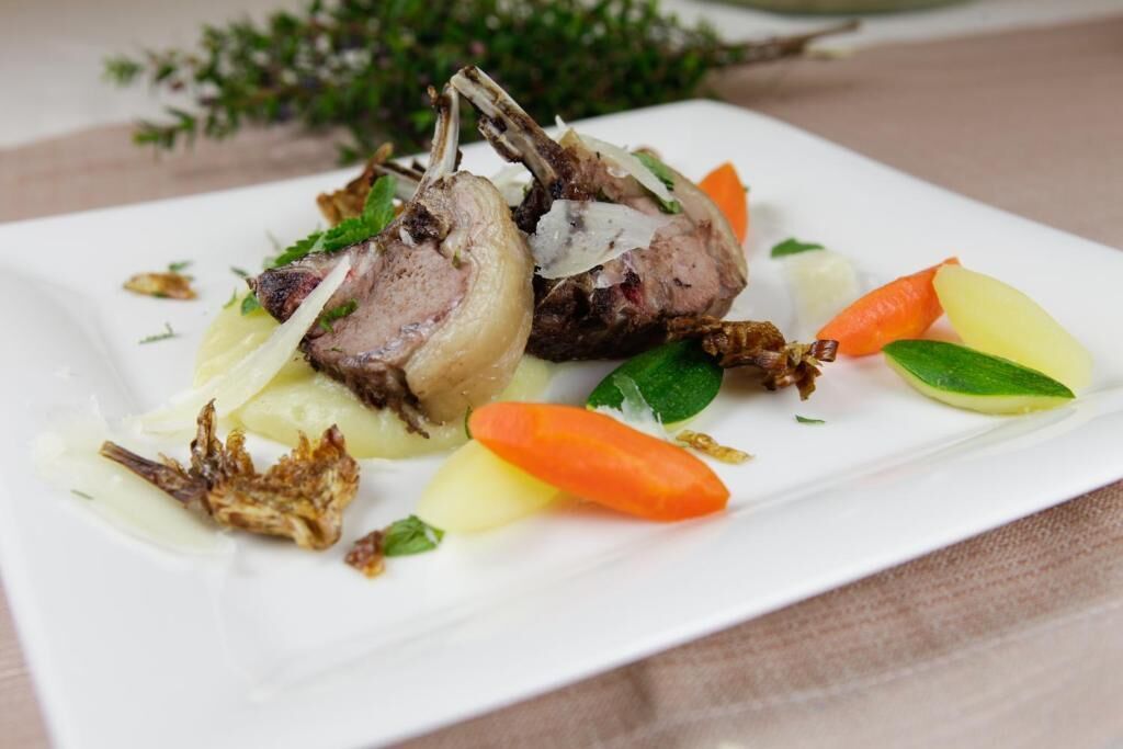 Ein Teller mit Lammkoteletts, Kartoffeln und Karotten.