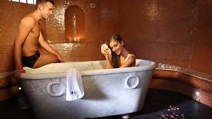 Eine Badewanne in einem Raum mit gefliesten Wänden und einem Spiegel.