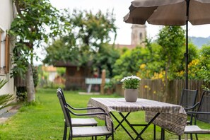 An outdoor patio with a table and chairs, a potted plant, and a view of a building with a bell tower. - Studio Apartment 'Weinangerhof Apartment Birnbaum' with Mountain View, Wi-Fi and Air Conditioning (Appiano)