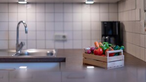 Eine Küche mit modernem Design, ausgestattet mit einem Spülbecken, einer Kaffeemaschine und einer Holzkiste voller Gemüse.