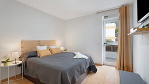 A modern bedroom with a bed, bedside table, lamp, and a view through a glass door. - Vacation Apartment 'Vivir Bajamar' with Sea View, Balcony and Wi-Fi (Bajamar)