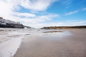 Ein Strand mit einer steinernen Wellenbrecher, ruhigen Wellen und einem klaren Himmel.