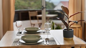A dining table with plates, cutlery, and a glass of water, set with a placemat and a potted plant. - Vacation Apartment 'Vivir Bajamar' with Sea View, Balcony and Wi-Fi (Bajamar)