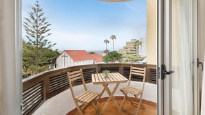 A balcony with a table and chairs, a potted plant, and a view of palm trees and buildings. - Vacation Apartment 'Vivir Bajamar' with Sea View, Balcony and Wi-Fi (Bajamar)