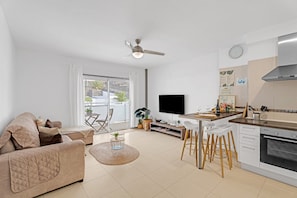 A modern living room with a sofa, TV, dining area, kitchen, and a balcony with plants. - Vacation Apartment 'Bajamar En Armonía' with Mountain Views and Wi-Fi (Bajamar)