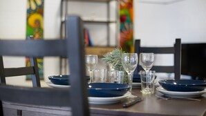 Una mesa de comedor dispuesta con platos azules, vasos transparentes y una pequeña planta.