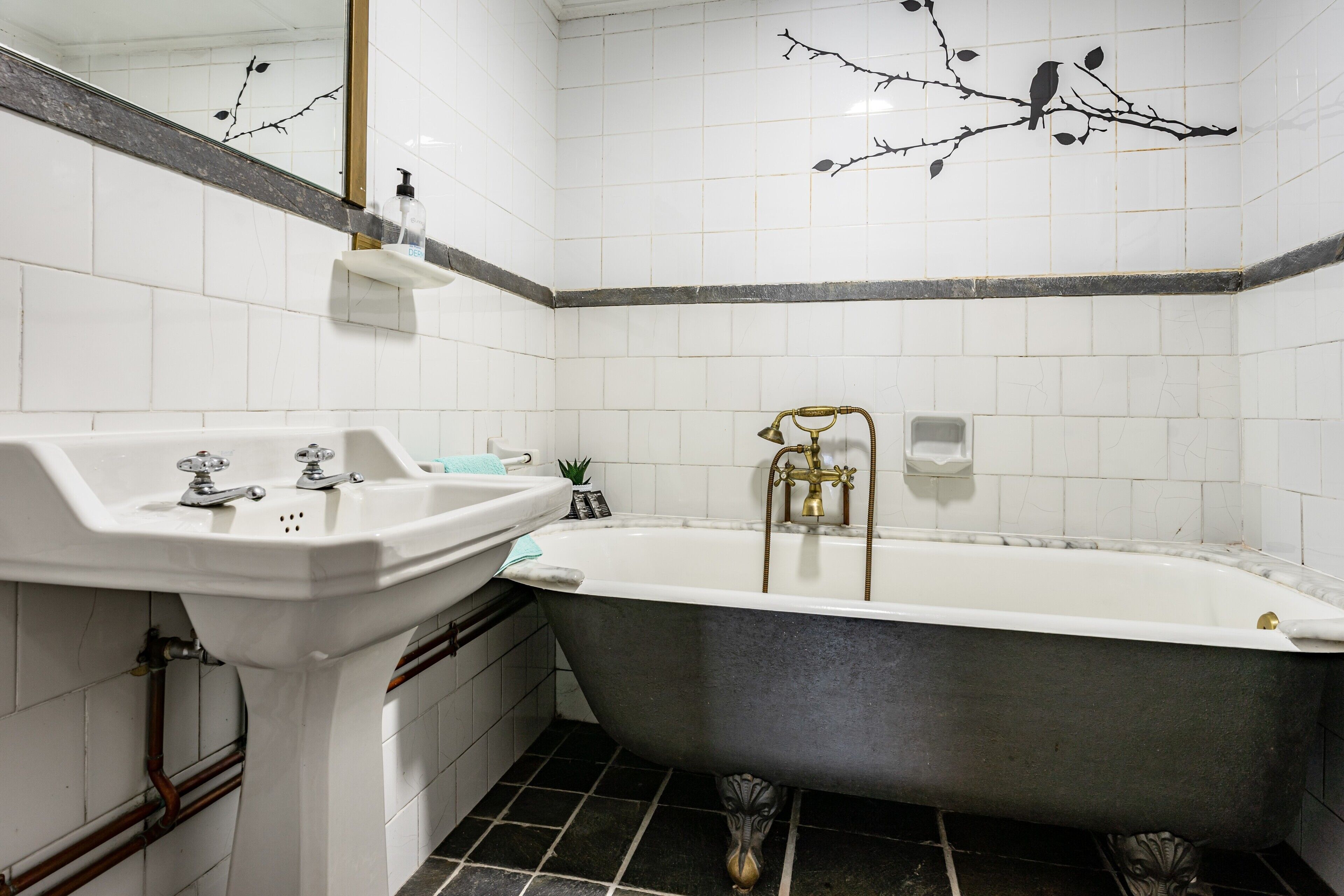 Een badkamer met een witte wastafel, een bad en een spiegel.