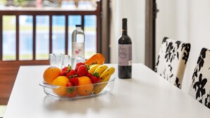 A dining table with a fruit bowl, a bottle of wine, and a glass of water. - Vacation Apartment 'Apto El Mocan Swimming Pool 2bed' with Shared Pool, Private Terrace and Wi-Fi (Palm-Mar)