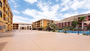 A hotel courtyard with multiple buildings, a swimming pool, and a clear sky. - Vacation Apartment 'Apto El Mocan Swimming Pool 2bed' with Shared Pool, Private Terrace and Wi-Fi (Palm-Mar)