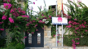 A boutique hotel entrance with a stone facade, two black doors, and a signboard. - Cotton Boutique Hotel (Bodrum)