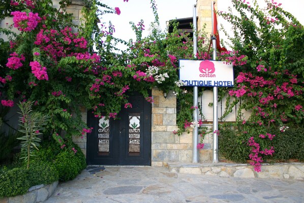 A boutique hotel entrance with a stone facade, two black doors, and a signboard. - Cotton Boutique Hotel (Bodrum)