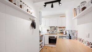 A kitchen with white cabinets, a wooden countertop, a tiled backsplash, and a hanging oven mitt.