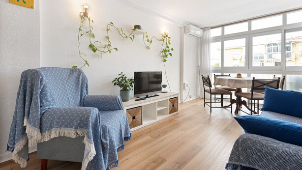 A living room with a TV, sofa, and dining area.
