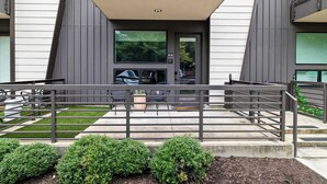 A modern building with a flat roof, a balcony, and a gated entrance. - Charming DT ATX Studio / Mins to Rainey St / Patio (Austin)