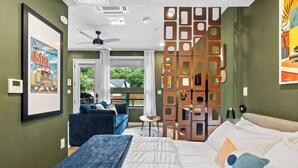 Una camera d'albergo con un letto, un divano blu, un tavolino, un pannello decorativo in legno e vista all'esterno.