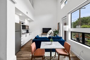 Une cuisine moderne avec des meubles blancs, un canapé bleu et une table à manger avec des chaises.