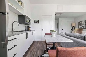 Een moderne keuken met witte kastjes, een roestvrijstalen koelkast en een inbouwmagnetron.