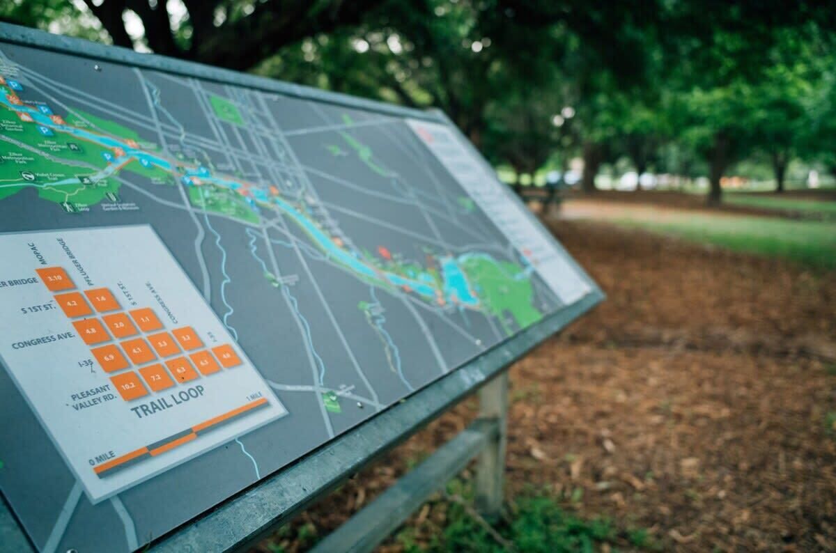 A map with a trail loop and a sign indicating distances to various points.